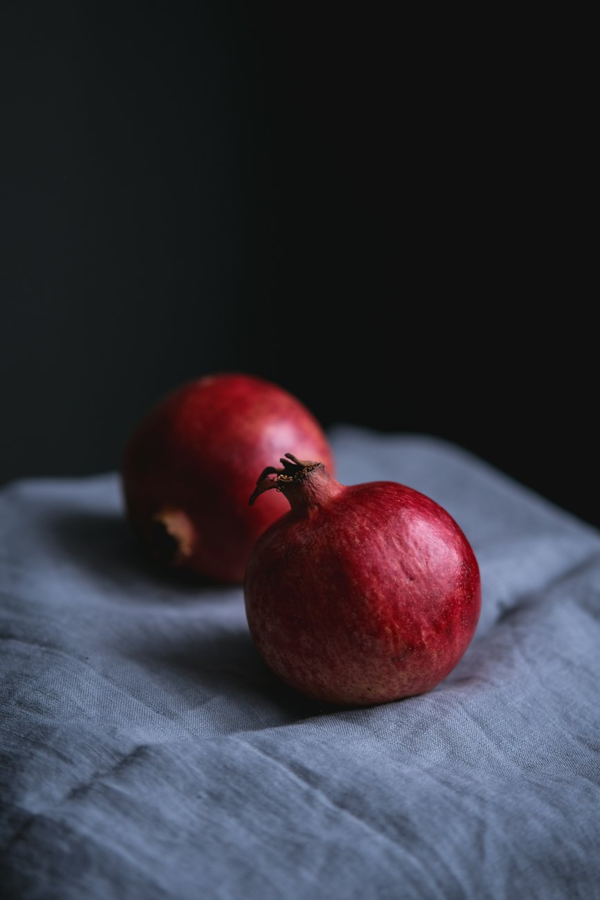 Two red apples on blue cloth in low light