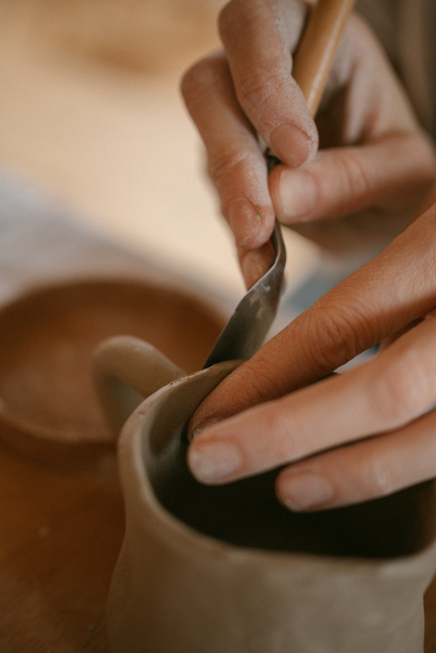 Hands trimming a clay pot